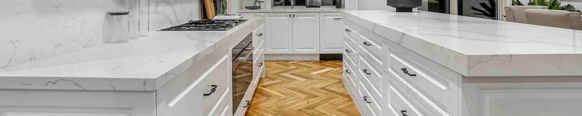 Bright kitchen with white cabinets and herringbone patterned hardwood floors installed in Falls Church, VA